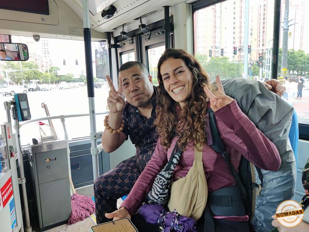 Tatiana sonriendo junto a un pasajero chino en un autobús urbano durante su viaje por libre por China