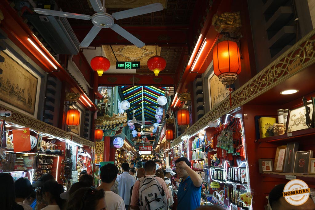 Calle Wangfujing en Pekín con puestos de souvenirs iluminados, linternas rojas colgantes y multitud de visitantes