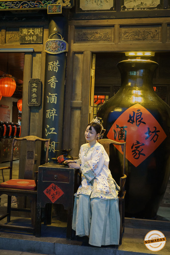 Mujer con traje tradicional chino posando frente a una tienda decorada con símbolos culturales en Pingyao