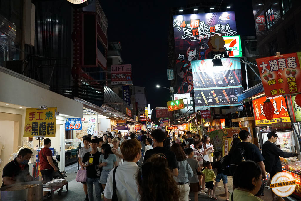 Gente paseando y comprando comida en Fengjia Night Market de noche