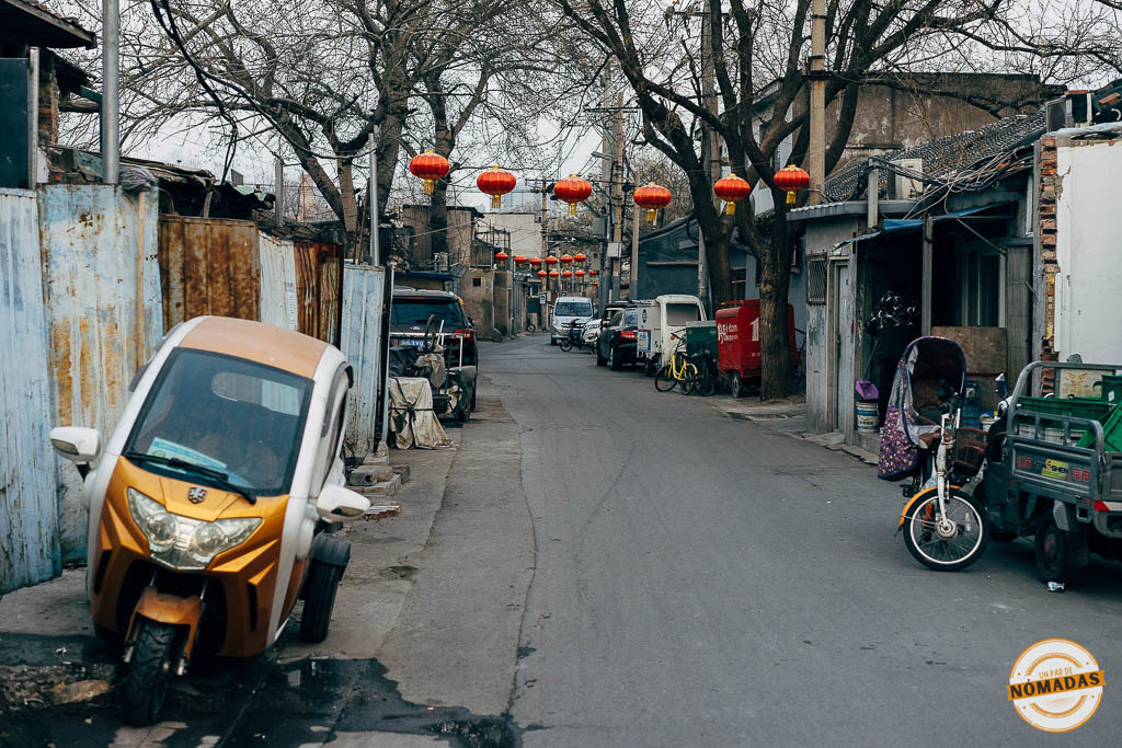 Hutongs de Pekín: calle estrecha con faroles rojos, motos eléctricas y casas tradicionales en uno de los barrios históricos de la ciudad