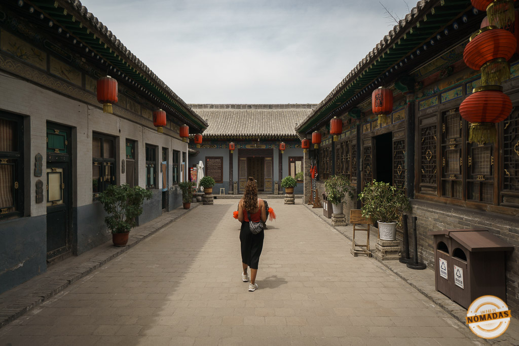 Tatiana caminando por un patio tradicional decorado con faroles rojos en Pingyao, arquitectura típica de la ciudad antigua