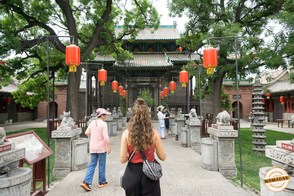 Tatiana caminando entre esculturas de piedra y faroles rojos hacia el Templo Chenghuang en Pingyao