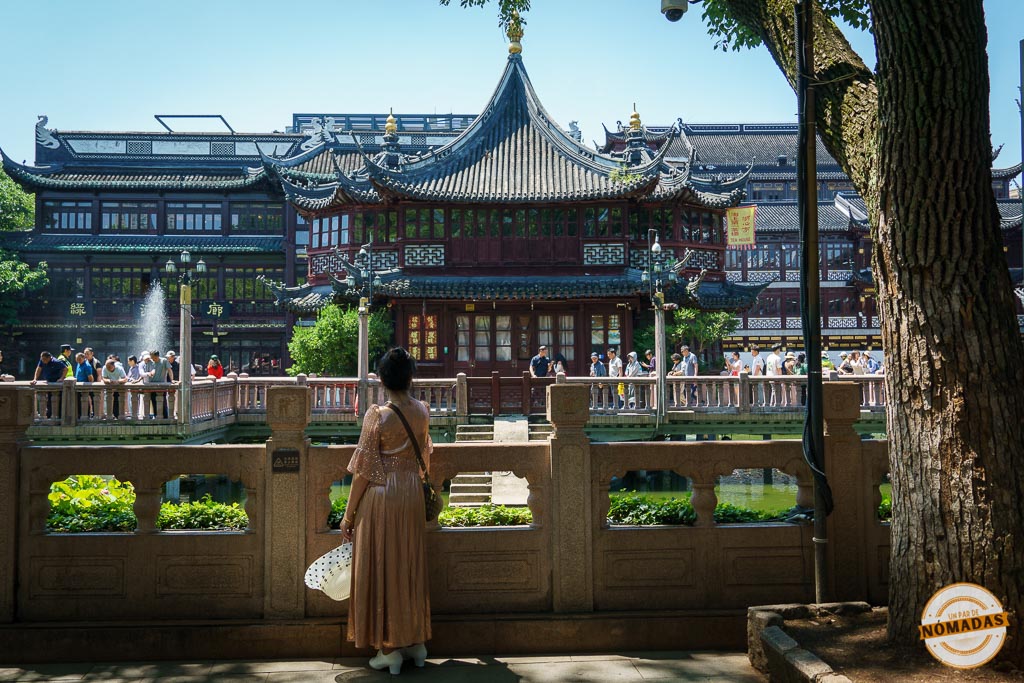 Turista mirando un pabellón tradicional junto al estanque lleno de carpas en Yu Garden, Shanghái
