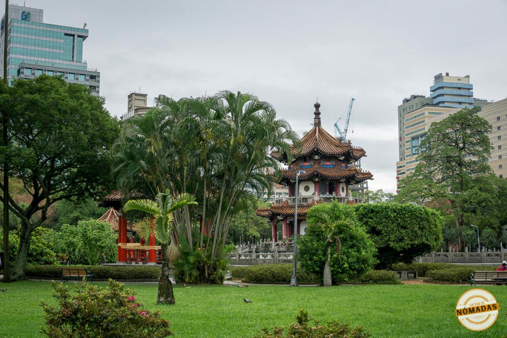 Vista del pabellón tradicional chino dentro del 2-28 Peace Memorial Park en Taipéi, rodeado de jardines y edificios urbanos.