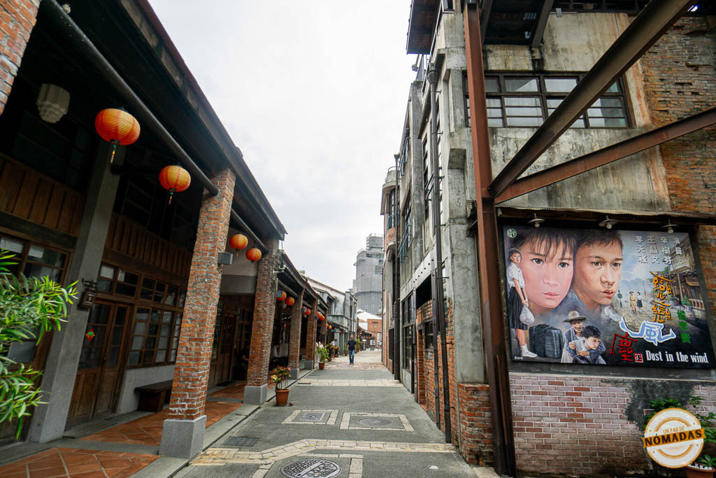 Calle del Bopiliao Historical Block con farolillos rojos colgando, edificios de ladrillo y cartel de película clásica taiwanesa.