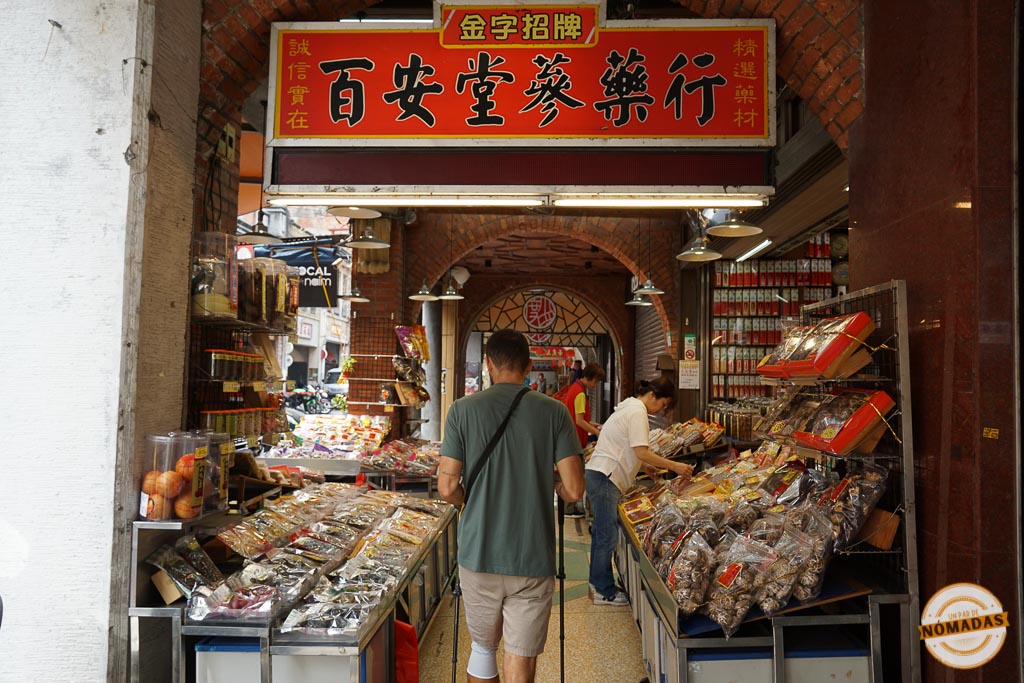 Oscar recorriendo una tienda tradicional de Dihua Street, rodeado de productos medicinales y alimentos secos taiwaneses.
