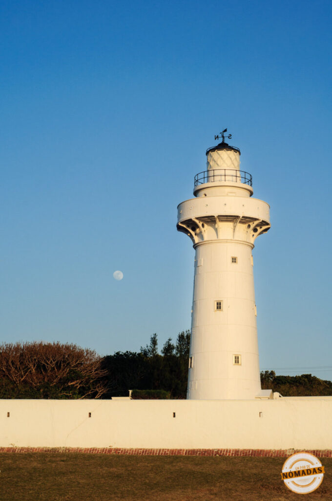 Faro blanco de Eluanbi al amanecer con la luna aún visible en el cielo