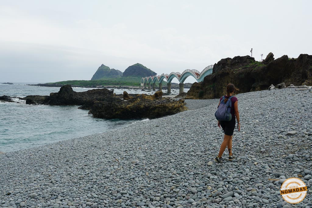 Qué ver en Taitung en 2 días: Mujer caminando hacia el puente Sanxiantai sobre una playa de piedras en Taitung, Taiwán