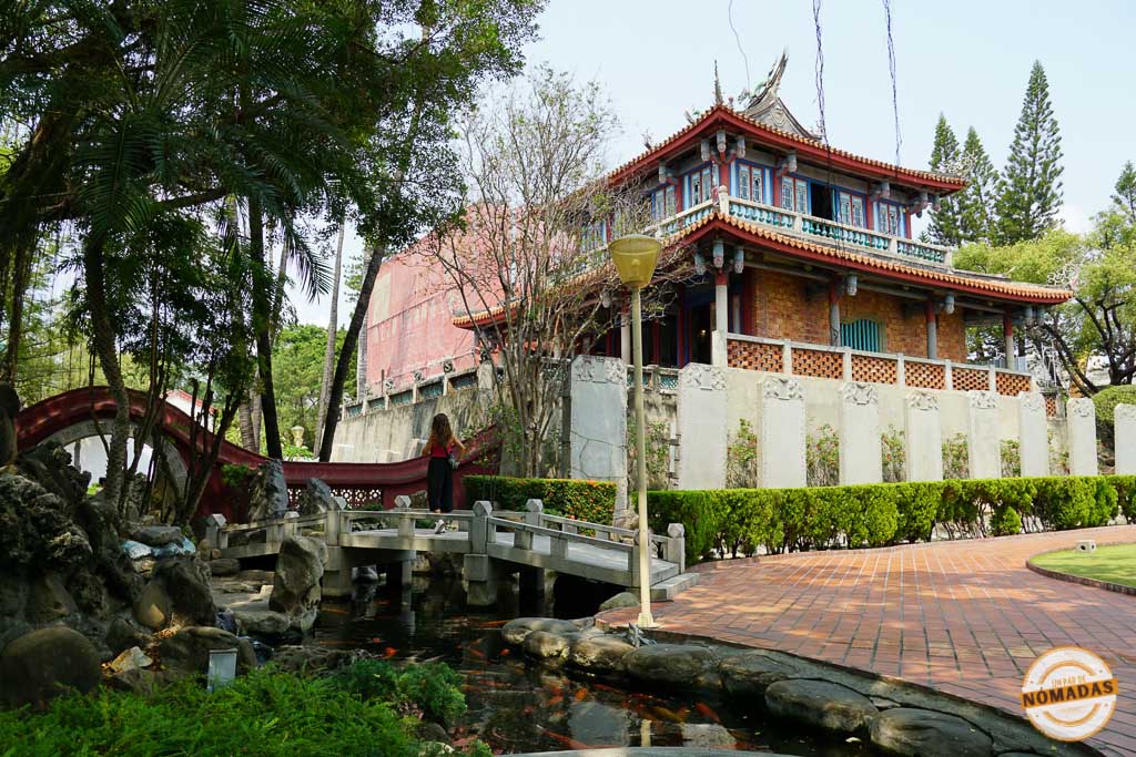 Tatiana cruzando un puente tradicional en Fort Provintia, Tainan, rodeada de jardines