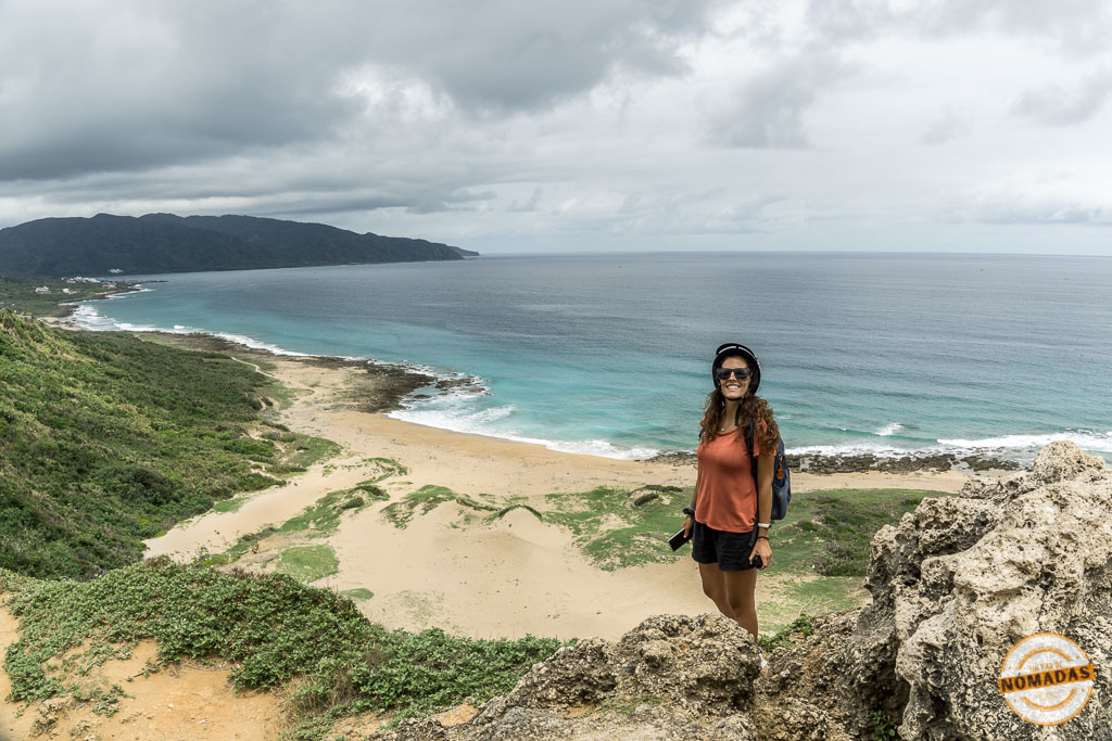 Viajera sonriendo con vistas al mar y colinas desde Fengchuisha