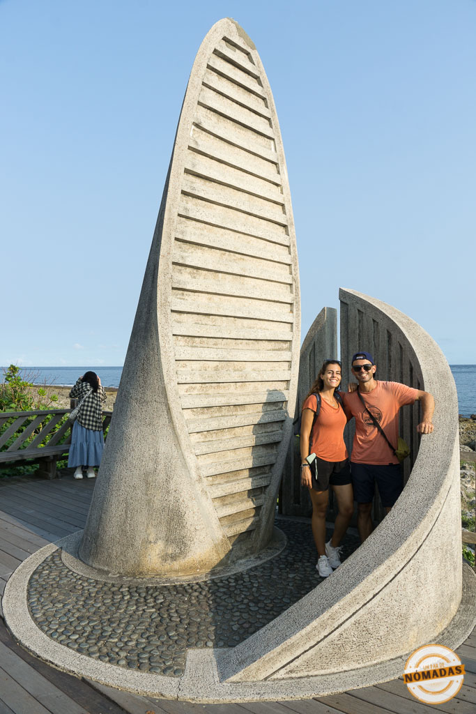 Pareja de viajeros junto al monumento en forma de vela en el punto más al sur de Taiwán
