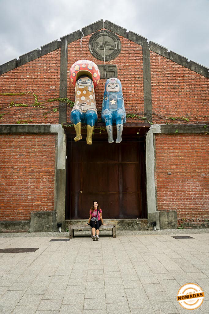 Tatiana sentada frente a una fachada artística en el Pier-2 Art Center de Kaohsiung
