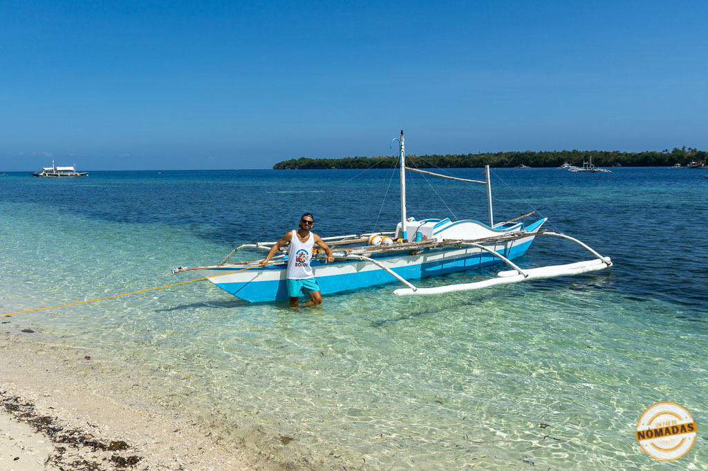 Oscar junto a una bangka tradicional en la orilla de aguas cristalinas en la isla de Camotes, Filipinas.
