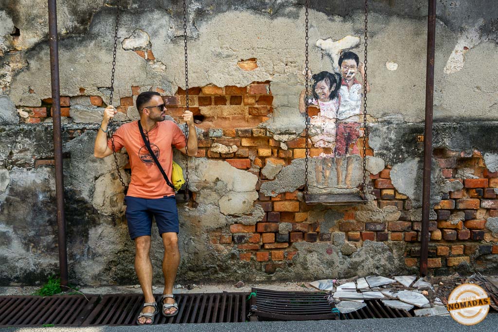 Oscar sentado en un columpio junto a un mural interactivo en George Town