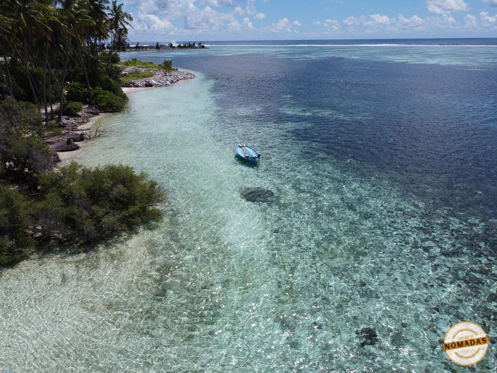 Vista aérea de la costa de Dhiffushi con vegetación y un barco en el agua