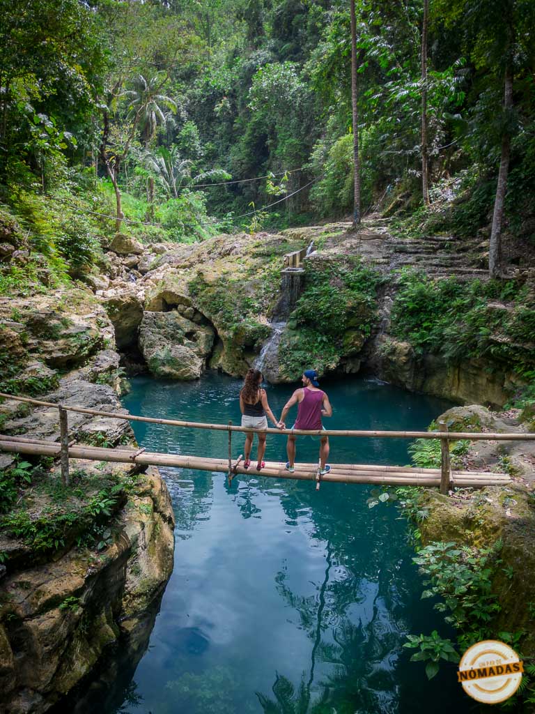 Pareja de espaldas sobre un puente de bambú sobre una piscina natural rodeada de vegetación tropical en Moalboal, Cebú, Filipinas.
Pareja de espaldas sobre un puente de bambú sobre una piscina natural rodeada de vegetación tropical en Moalboal, Cebú, Filipinas.