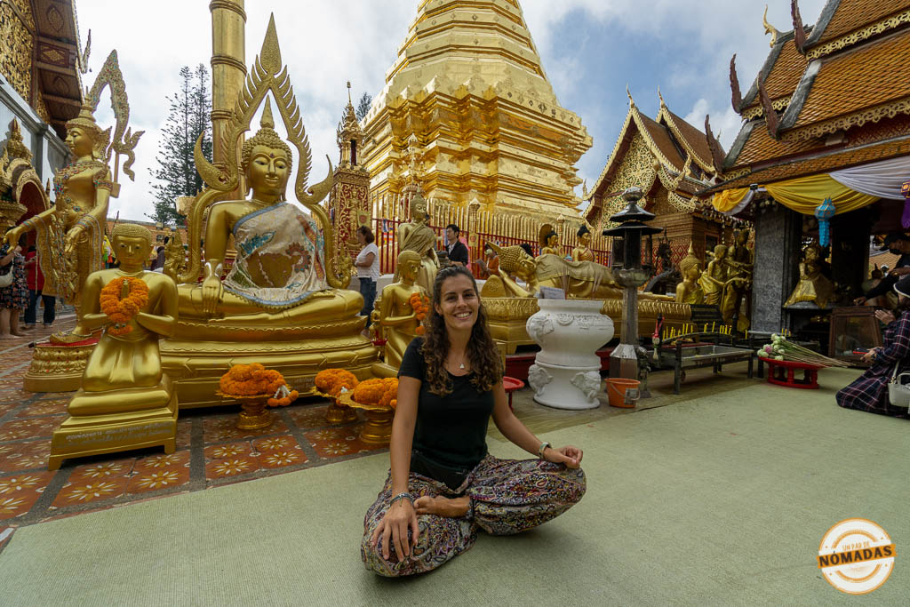 Tatiana meditando frente a budas dorados en el templo Doi Suthep en Chiang Mai, Tailandia