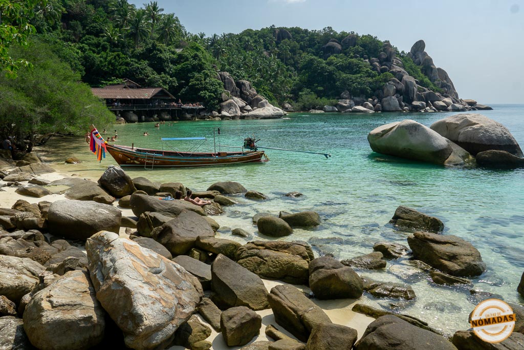 Barco longtail anclado en una pequeña cala de aguas turquesas en Koh Tao, Tailandia, rodeada de rocas y selva