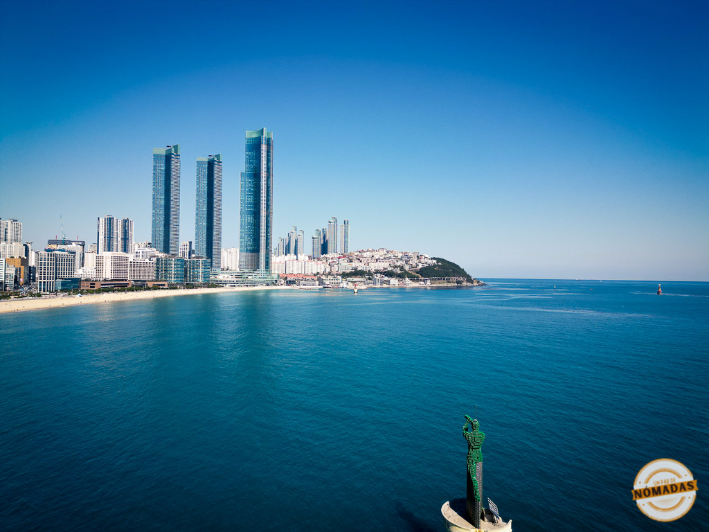 Vista aérea de la costa de Busán con rascacielos y escultura en el mar, imagen ideal para hablar de consejos prácticos antes de viajar
