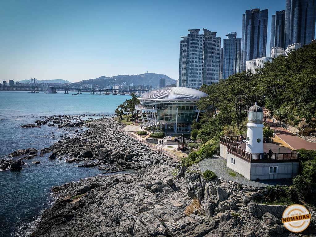 Vista aérea de Dongbaek Island con el edificio Nurimaru APEC House y el skyline de Busán al fondo, uno de los lugares más fotogénicos que ver en Busán
