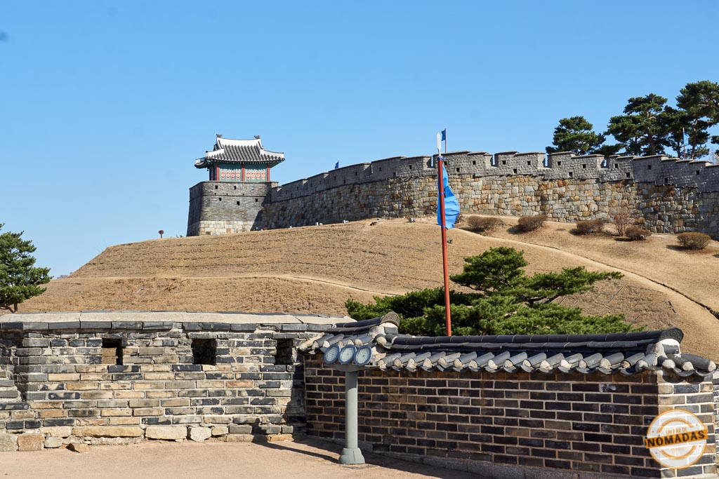 Vista panorámica de la muralla de piedra y una torre de vigilancia en la fortaleza de Hwaseong