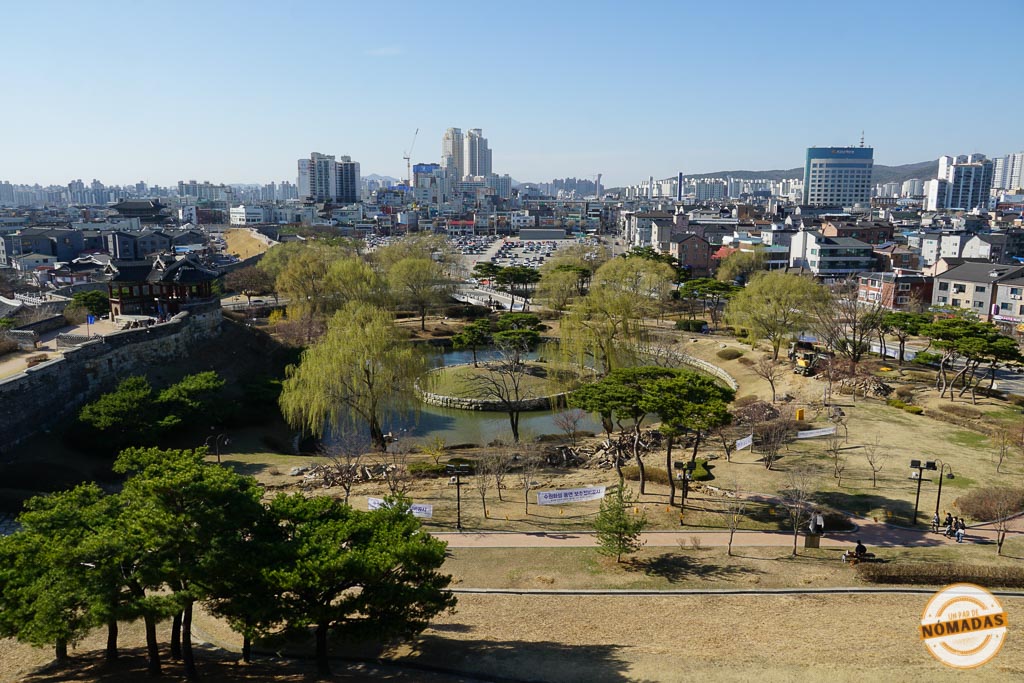 Vista aérea desde la muralla de Suwon con árboles y estanque al fondo
