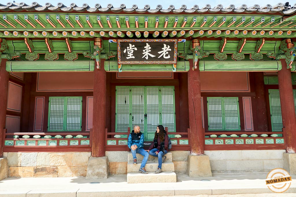 Pareja sentada en una antigua construcción coreana de madera y colores tradicionales en Suwon, Corea del Sur