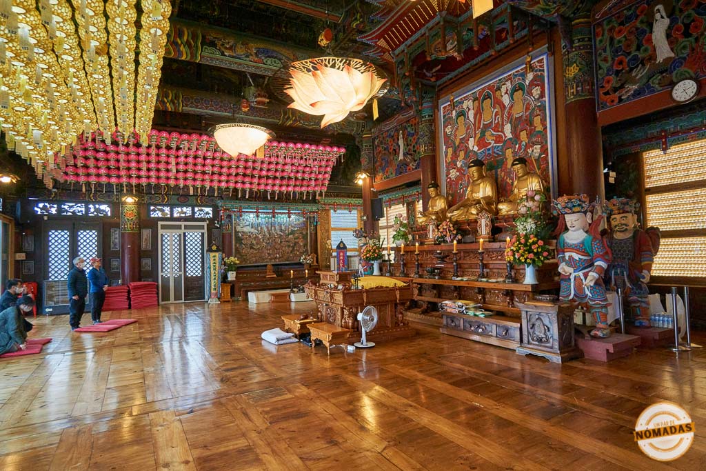 Sala principal del templo Jogyesa en Seúl, decorada con estatuas doradas de Buda, faroles de colores y detalles tradicionales