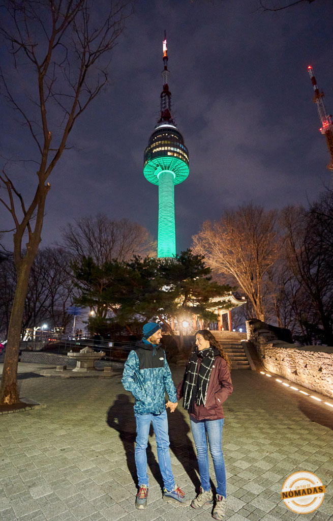 Pareja de viajeros de noche bajo la Torre N de Seúl iluminada, en el monte Namsan