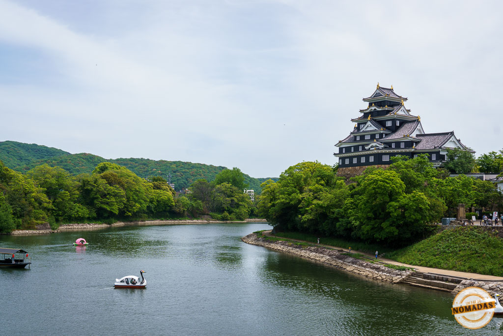 El castillo negro de Okayama visto desde el río Asahi con barquitas