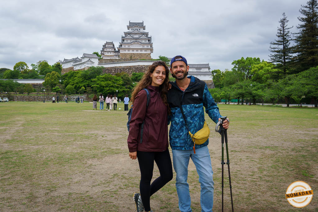 Un par de nómadas sonriendo con el castillo de Himeji a su espalda