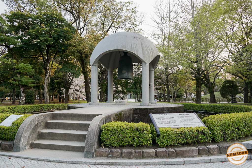 Campana de la Paz en el Cenotafio de Hiroshima rodeada de vegetación y paneles informativos