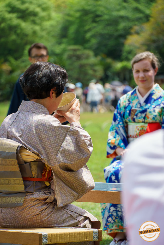 Mujer bebiendo té en ceremonia tradicional al aire libre en Okayama