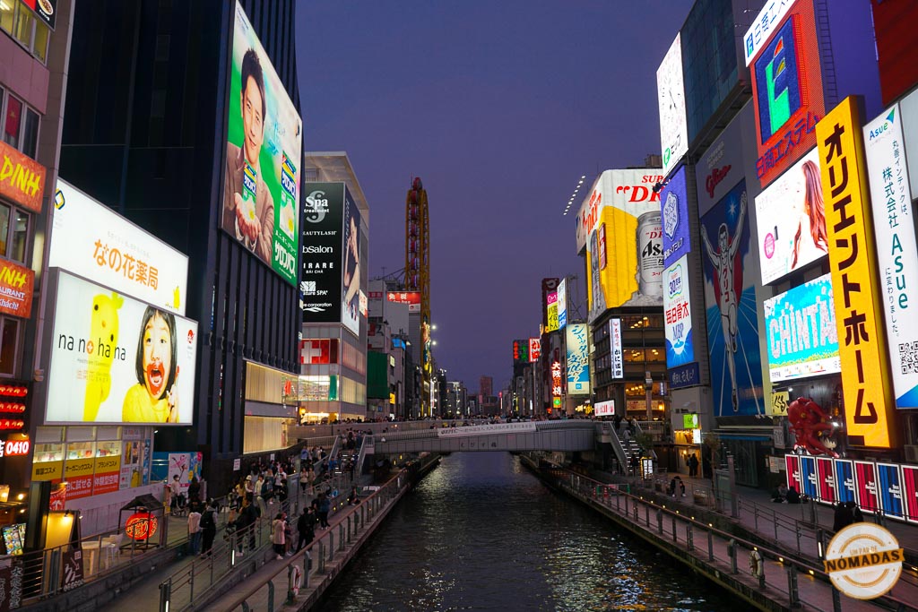 Vista nocturna del canal de Dotonbori en Osaka con carteles luminosos y ambiente animado, uno de los lugares más emblemáticos de la ciudad

