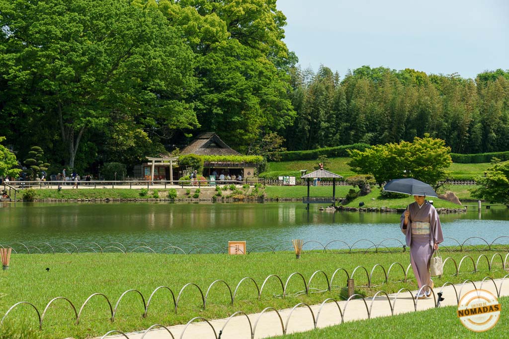 Mujer japonesa con kimono y sombrilla paseando junto al lago del jardín Kōrakuen