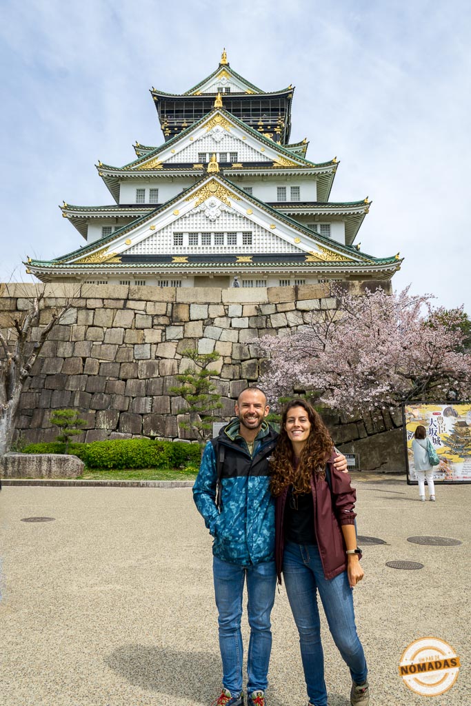 Pareja posando frente al castillo de Osaka con cerezos en flor durante la primavera, uno de los lugares más emblemáticos de la ciudad
