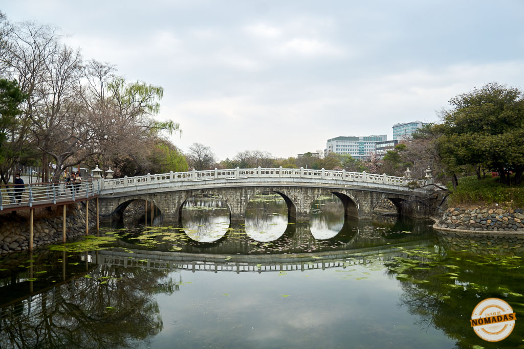Puente tradicional de piedra reflejado en el lago del parque Duryu