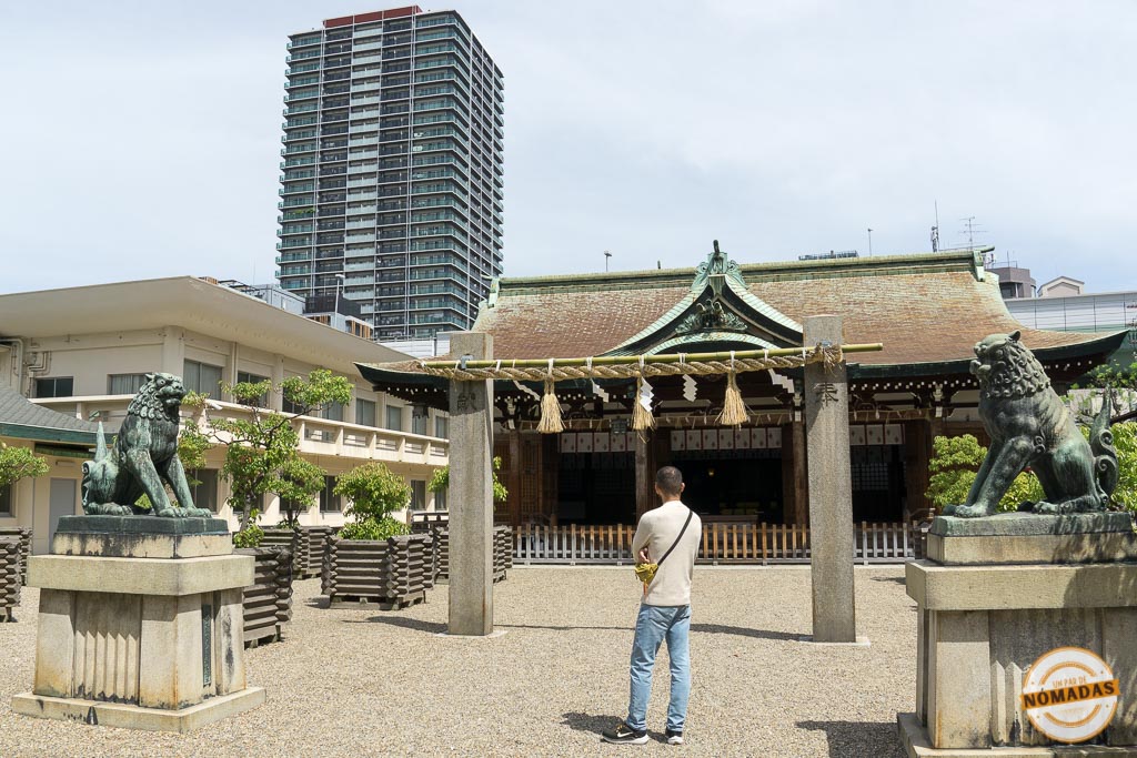 Oscar frente al santuario Imamiya Ebisu con edificios modernos de fondo.

