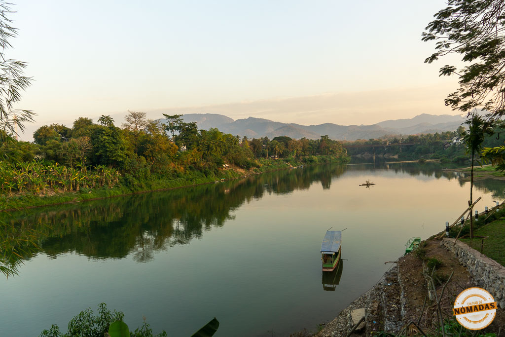 Barca flotando en el río Mekong al atardecer, vista desde la orilla en Luang Prabang.
