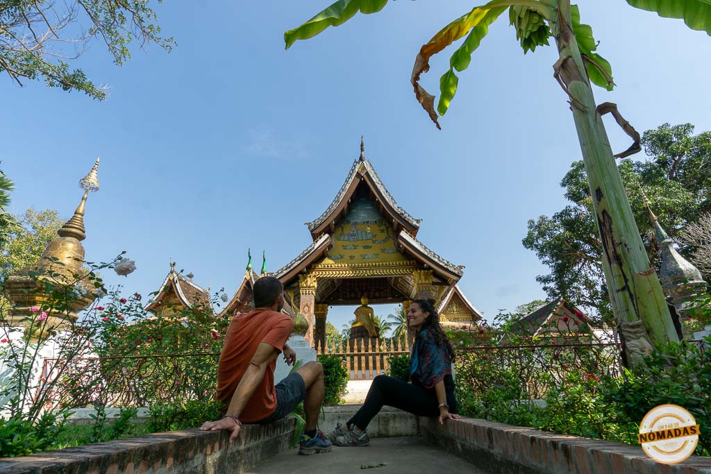 Pareja contemplando la entrada del Wat Aham, un templo budista rodeado de jardines en Luang Prabang.
