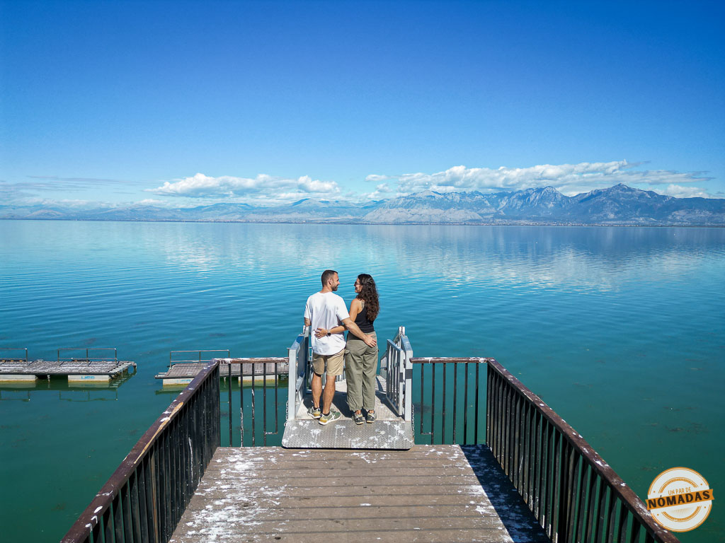Pareja abrazada en un muelle de madera mirando las vistas del Lago Skadar (Lago de Shkodër) y las montañas, una visita imprescindible al viajar a Albania por libre.