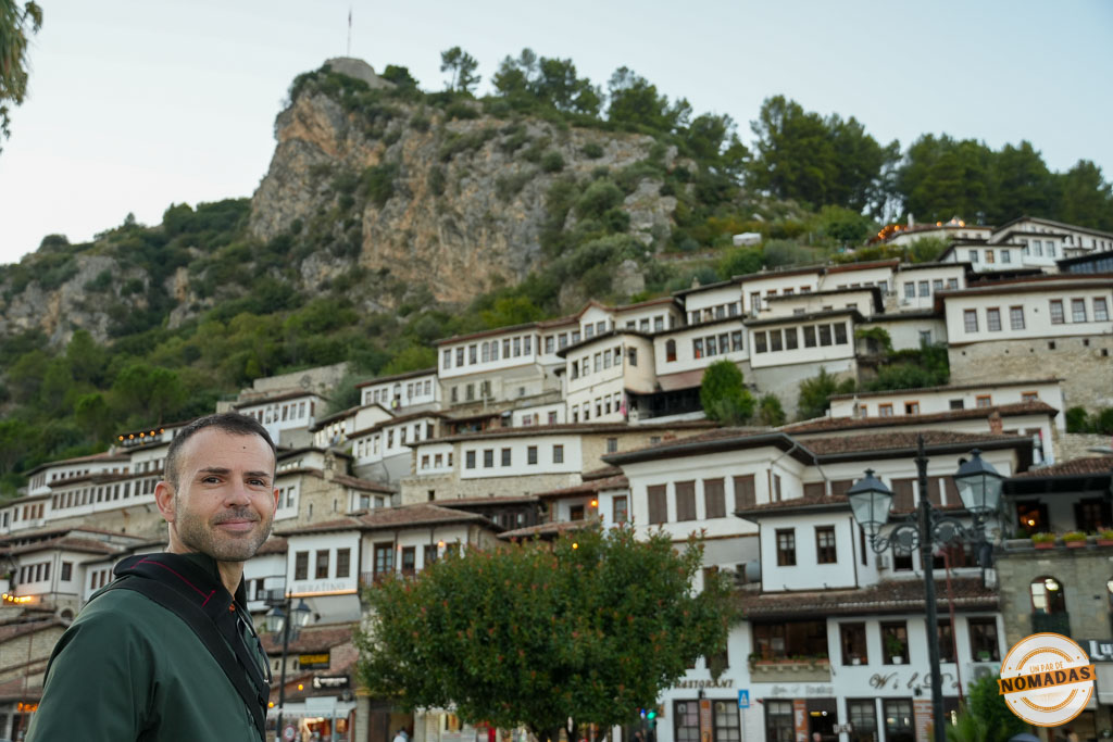 Hombre posando delante de las casas otomanas del barrio de Mangalem en Berat, Albania, con el castillo en la cima de la colina.