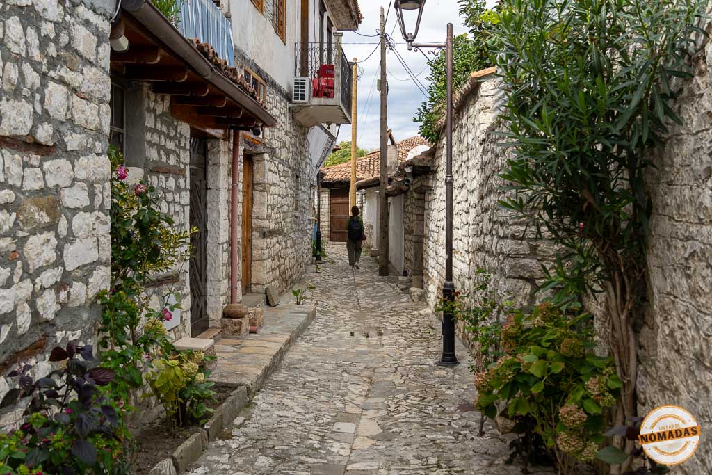 Callejuela empedrada dentro de las murallas del Castillo de Berat, con casas antiguas y vegetación
