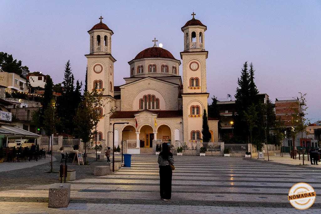 Mujer mirando la fachada iluminada de la Catedral Ortodoxa de San Demetrio al atardecer