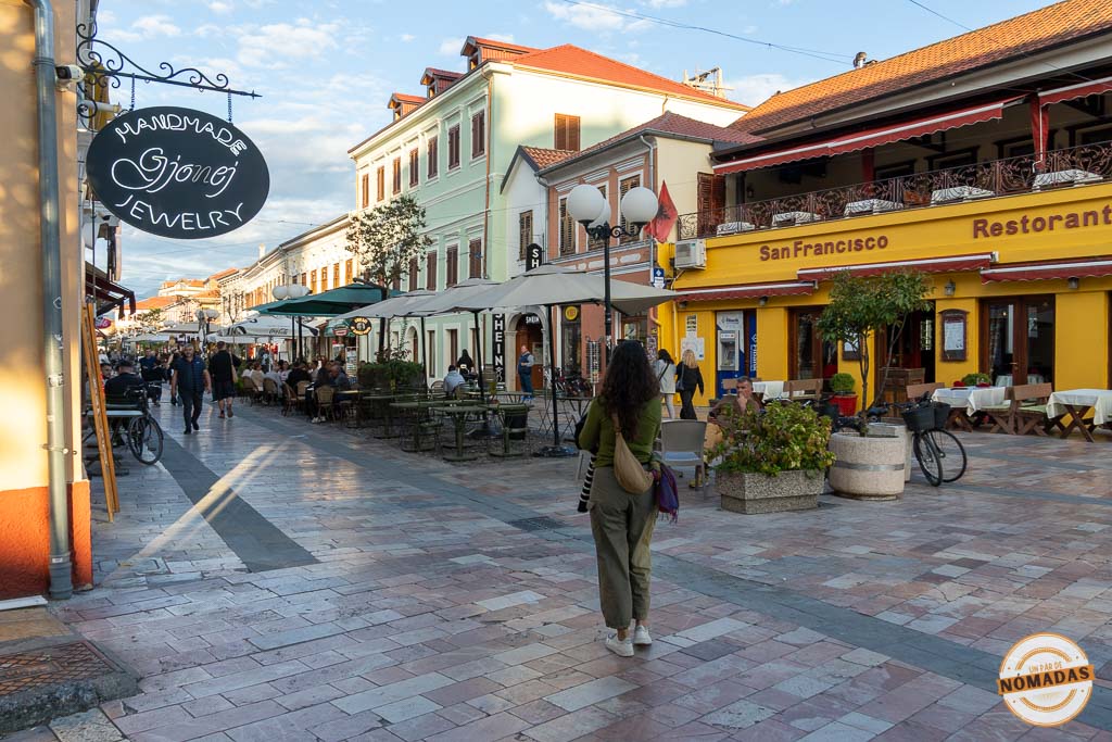 Mujer paseando por la calle peatonal Kolë Idromeno (Pedonalja), el centro histórico lleno de terrazas y edificios coloridos