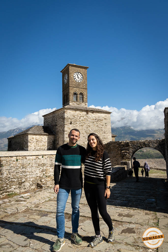 Pareja de viajeros posando delante de la Torre del Reloj del Castillo de Gjirokastër.