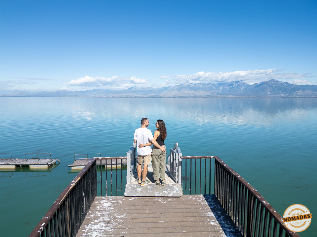 Pareja de viajeros en un muelle disfrutando de las vistas del Lago Shkodër (Lago Skadar), una visita imprescindible que ver en Shkodër.