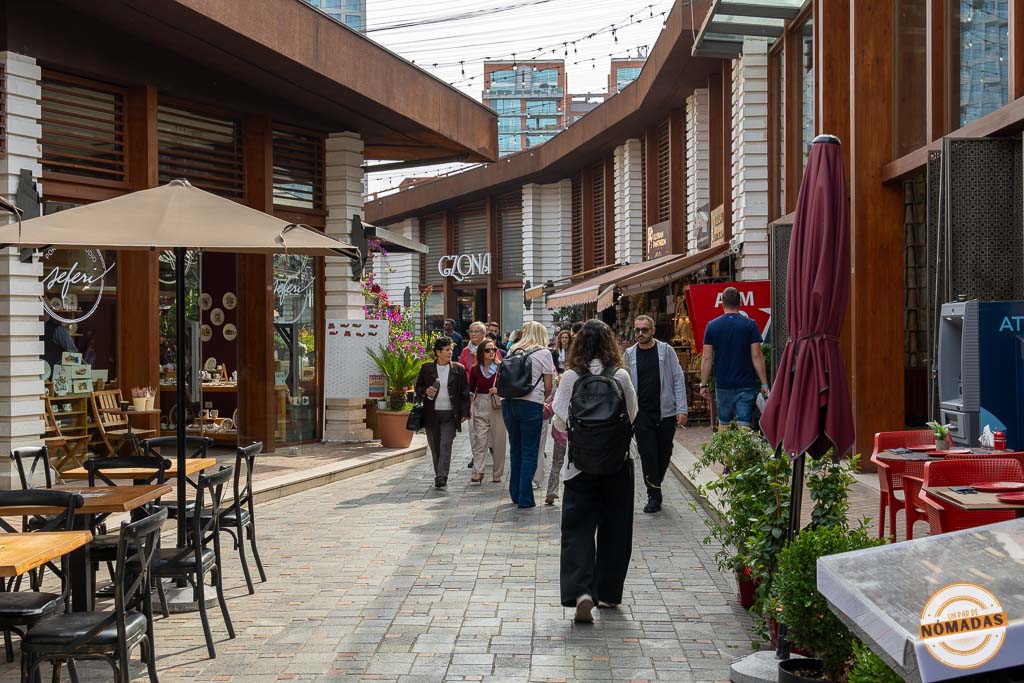 Calle peatonal animada dentro de los muros del antiguo Castillo de Tirana, repleta de restaurantes y tiendas.