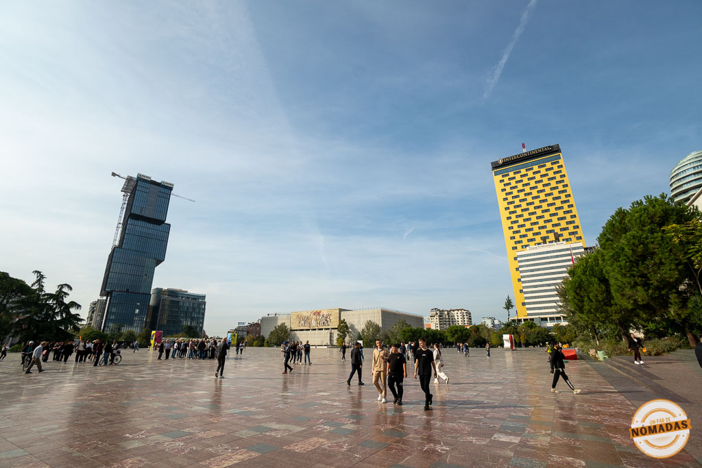 Vista amplia de la Plaza Skanderbeg, con el mosaico del Museo Histórico Nacional al fondo flanqueado por modernos rascacielos.